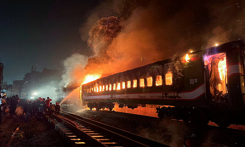 Firefighters try to extinguish a fire caught on a passenger train, ahead of the general election in Dhaka,